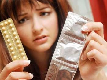Девушка смотрит на таблетки и презервативы