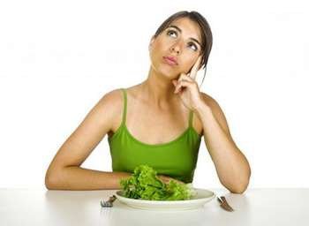 Девушка в задумчивости перед тарелкой с листом салата