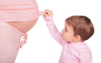 Мальчик смотрит на живот беременноймамы